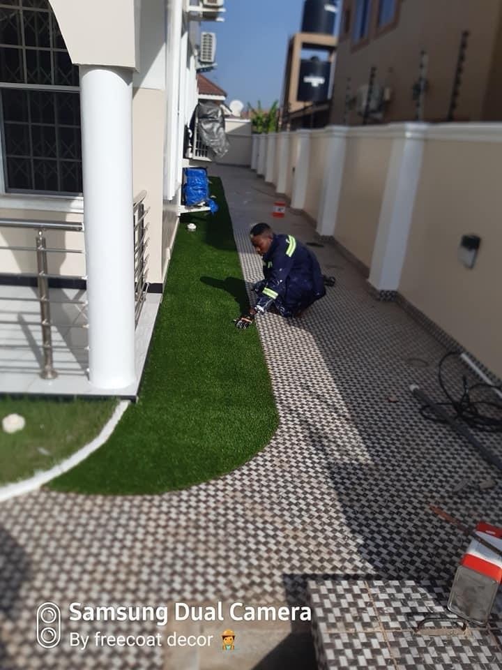 Artificial grass installation along curved pathway beside villa in East Legon
